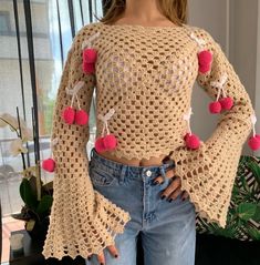 a woman is wearing a crochet top with pom - poms on it