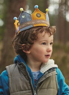 a young boy wearing a crown in the woods