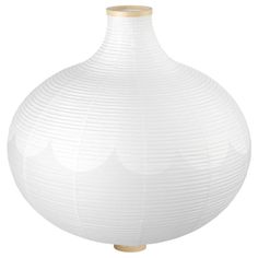 a large white vase sitting on top of a wooden table next to a lamp shade