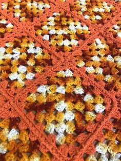 an orange and white crocheted blanket is laying on the floor