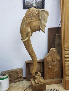 an elephant carved from wood in front of a painting on the wall and other items