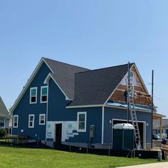 a blue house with a ladder up to it's roof that is under construction