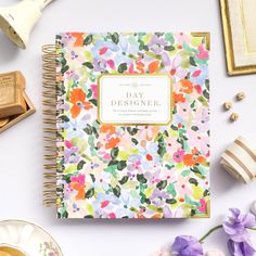 a floral notebook with the words day designer on it next to some flowers and other items