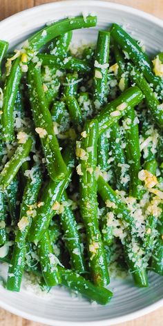 a white plate topped with green beans covered in parmesan sprinkles