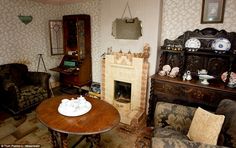 a living room filled with furniture and a fire place next to a wallpapered wall