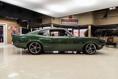 a green car is parked in a showroom