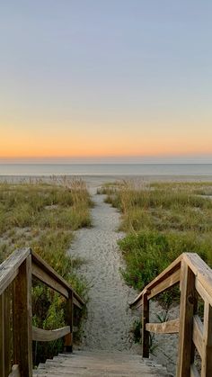 two wooden steps leading to the beach at sunset