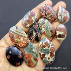 a hand holding several different colored rocks in it's palm, with the word peace written on them