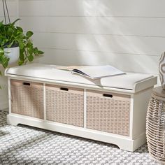 a white bench with wicker baskets and a book on it next to a potted plant