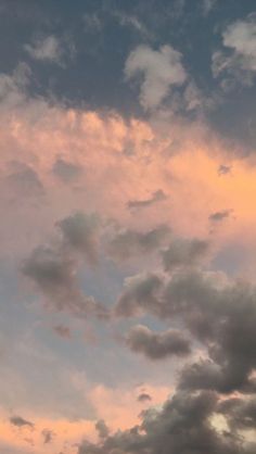 the airplane is flying high in the sky with clouds behind it and an orange glow