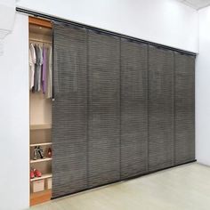 an empty room with sliding doors and clothes on the shelves in front of the closet