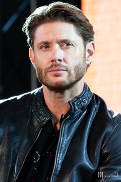 a close up of a person wearing a leather jacket and looking off to the side