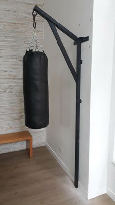 a black punching bag hanging from the wall next to a bench and wooden flooring