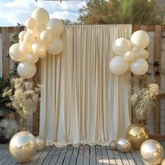 an outdoor event with balloons and flowers on the side wall, in front of a backdrop