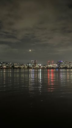 the city lights are reflected in the water at night, and there is no image to provide a caption for