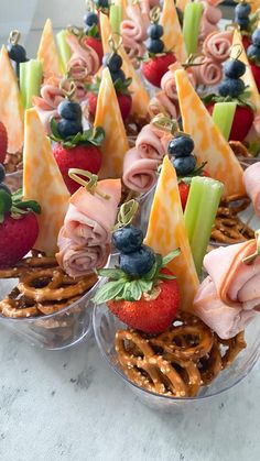 several small trays filled with pretzels, strawberries and other food items