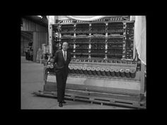 a man in a suit standing next to an old machine that is being worked on