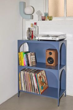 a blue shelf with some records and a stereo on it in a room next to a mirror