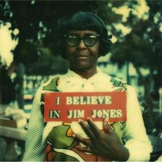 a woman holding a sign that says i believe in j m jones