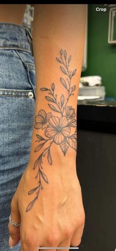 a woman's hand with a flower tattoo on her left arm and the wrist