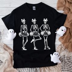 Cheerleader Skeletons, Cheer Shirt, Halloween Shirt, Spooky Season, Spooky Shirt, Trendy Halloween, Cheerleading Shirt Cheer Mom Shirt, Dark Clowncore, Dark Memecore, Skinny Shirt, Retro Graphic Tee, Goth Shirt, Goth Cheerleader This Soft-style t-shirt puts a new spin on casual comfort. Made from very soft materials, this tee is 100% cotton for solid colors. Heather colors and sports grey include polyester. The shoulders have twill tape for improved durability. There are no side seams. The colla Halloween Cheer Shirts, Black Short Sleeve Shirt For Costume Party, Cotton Tops With Character Print For Costume Party, Halloween Novelty Top For Fan Merchandise, Halloween Novelty Tops For Fans, Spooky Cotton Tops For Costume Party, Novelty Crew Neck Top For Costume Party, Punk Skull Print Shirt For Halloween, Spooky Cotton Top For Costume Party