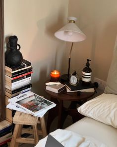 a bed room with a lamp a table and some books on top of the bed