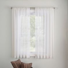 a chair sitting in front of a window next to a wooden floor and white walls