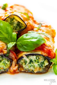 a white plate topped with pizza covered in sauce and spinach leaf garnish