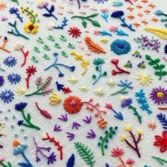 an embroidered cloth with many different colored flowers and plants on it's side,