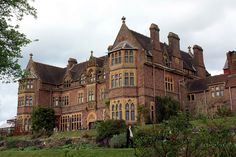 an old brick building with many windows on the top floor and lots of greenery in front of it