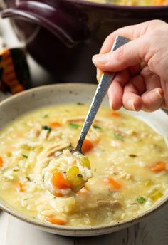 a person holding a spoon over a bowl of soup