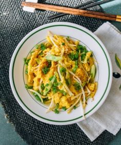 a white bowl filled with food next to chopsticks on top of a table