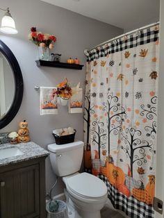 a white toilet sitting next to a bathroom sink under a mirror with fall decorations on it