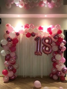 the balloon arch is decorated with pink, white and red balloons that spell out the number eighteen