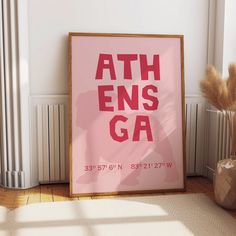 a pink poster with the words ath ens ga on it next to a plant