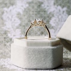 an engagement ring sitting on top of a white box