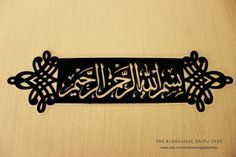 an arabic calligraphy is displayed on a wooden surface