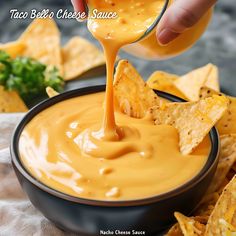 a person dipping cheese into a bowl of nachos