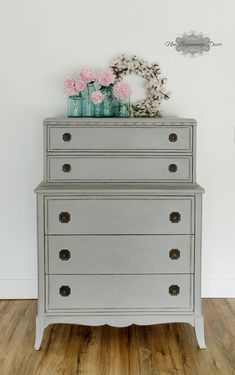 an old dresser with flowers and vases on top