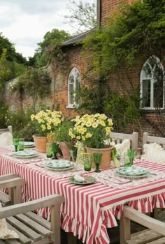 an outdoor table with flowers and plates on it