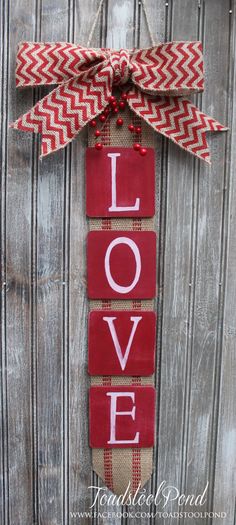 a love sign hanging on the side of a wooden door with a red and white bow