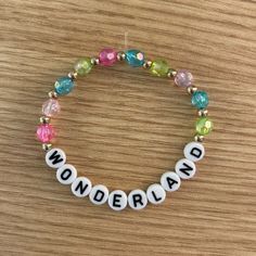 a beaded bracelet with the word wonderland written in white and multicolored beads