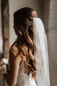 a woman in a wedding dress with a veil on her head and flowers in her hair