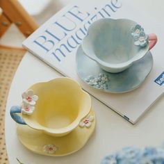 two plates and a bowl on a table next to a book with blue flowers in it