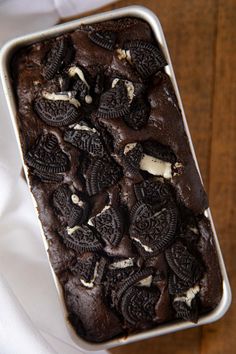 an oreo cookies and cream cake in a pan on a wooden table with white cloth