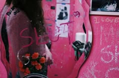 a woman standing in front of a pink mirror