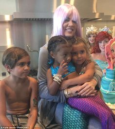 a group of children sitting next to each other in front of a cake with mermaids on it