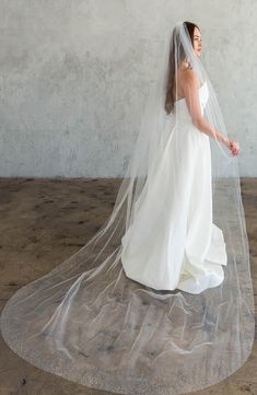 a woman in a white wedding dress is standing on the floor with her veil over her head