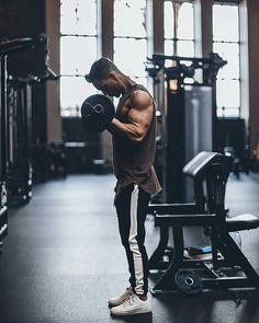 a shirtless man holding a dumbbell in a gym