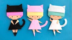 three origami cats are standing next to each other on a blue surface with one cat in the middle